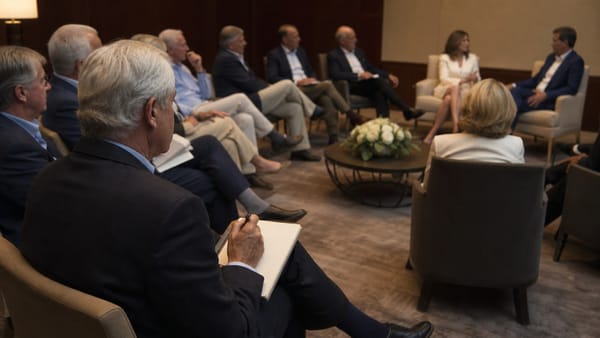 Audiencia ejecutiva reducida escucha una conversación moderada en un encuentro corporativo.