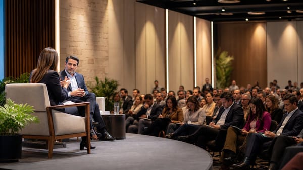 Moderadora conversa con un ejecutivo ante una audiencia de líderes empresariales.