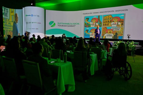 Audiencia escucha una ponencia en el Sustainable and Social Tourism Summit, en una sala con iluminación verde.